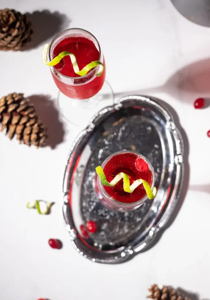 widok z góry na srebrną tacę z dwoma czerwonymi napojami i szyszkami.' loading='lazy' title=