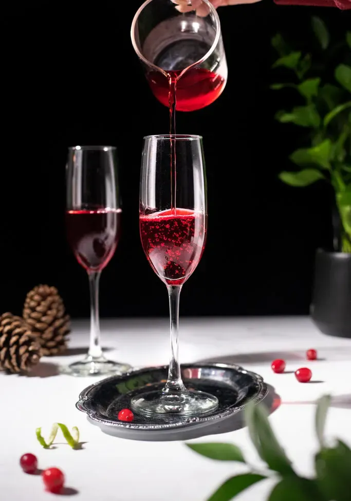 wlewając sok żurawinowy do kieliszka do szampana.' loading='lazy' title=