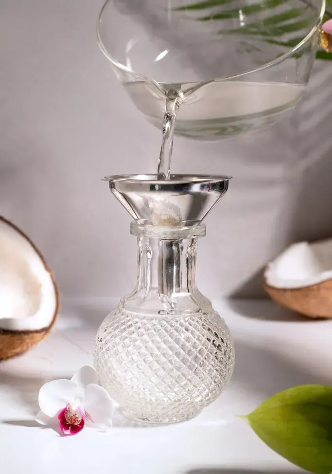 Einfacher Kokossirup aus einem Topf in eine schicke Glasflasche gießen.' title=