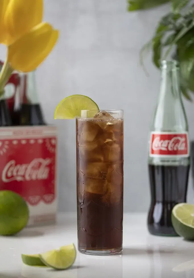 ein großes Glas Coca-Cola und Eis, garniert mit einem Limettenrad.' title=