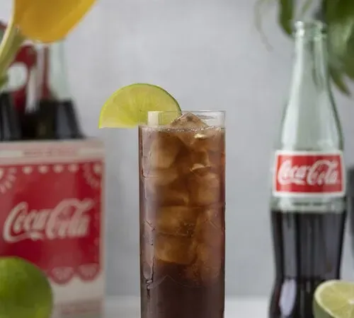 ein großes Glas Coca-Cola und Eis, garniert mit einem Limettenrad.' title=