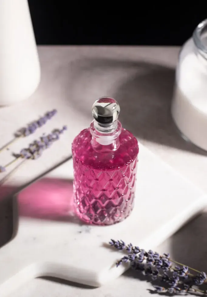 xarope roxo em garrafa de vidro chique em mármore branco.' loading='lazy' title=