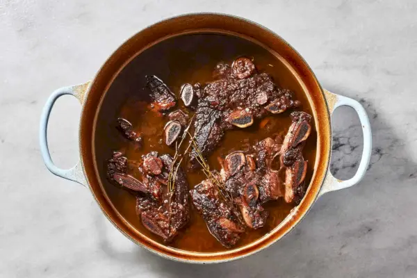 Um grande forno holandês com costelinha em molho de vinho tinto reduzido