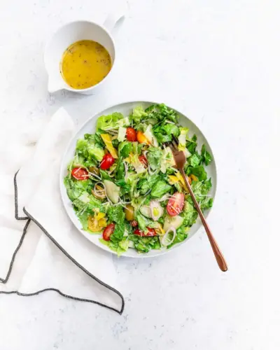 Salada picada em tigela branca com guardanapo e molho italiano