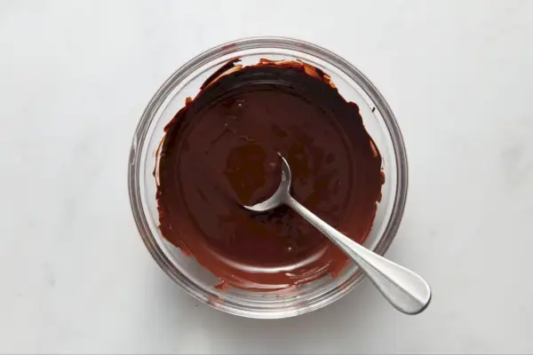 Un petit bol en verre avec du chocolat fondu agité avec une cuillère
