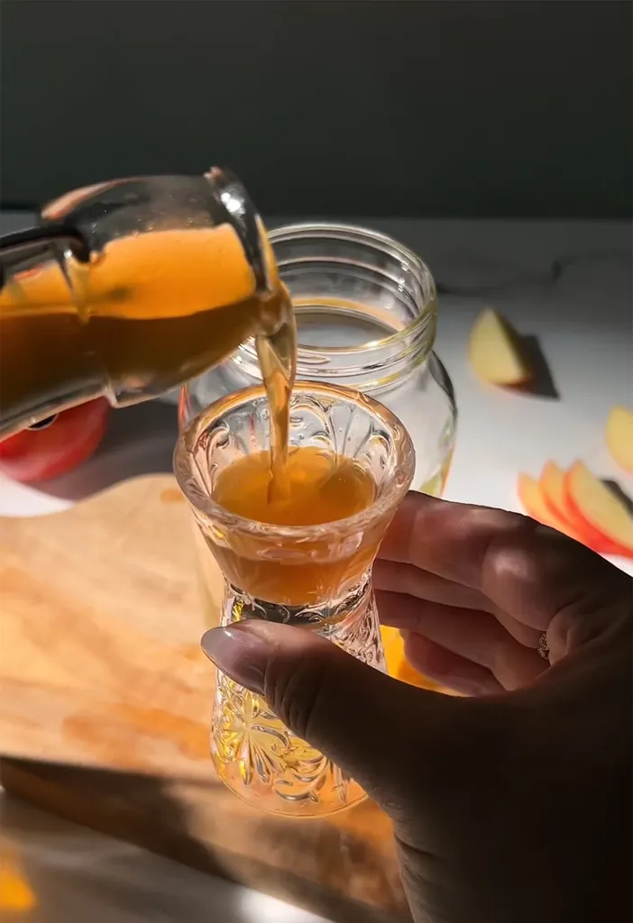 verser du sirop de couleur dorée de la bouteille au jigger en verre.' title=