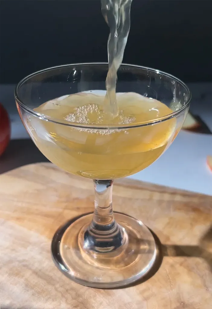 liquide de couleur dorée versé dans un verre coupé.' title=