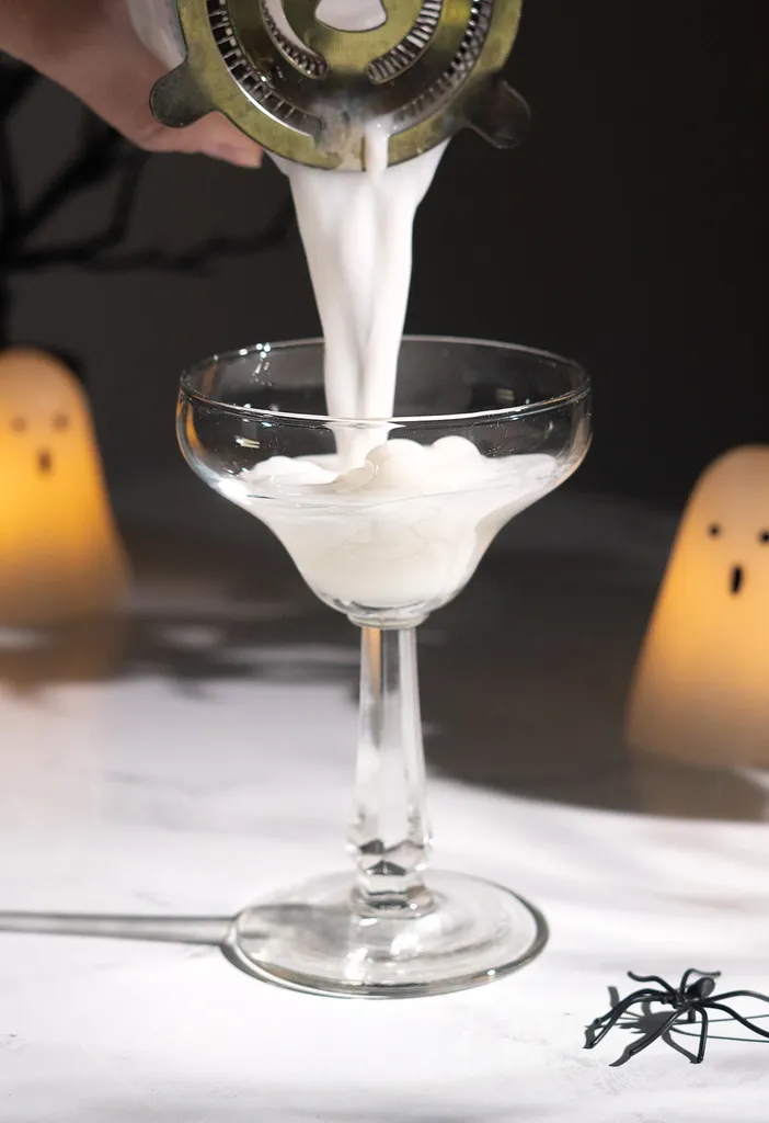 verser le liquide blanc d'un shaker à cocktail dans un verre à margarita.' loading='lazy' title=