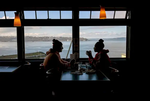 Una vista de los comensales comiendo junto a una ventana en un restaurante frente al mar en Seattle