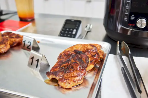 Um pedaço de frango cozido em uma assadeira ao lado da Fritadeira Instant Pot Pro Crisp & Air Fryer 8-Quart Multi-Use Pressure Cooker e Air Fryer