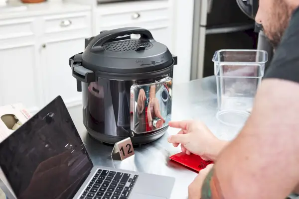 Pessoa olhando para um laptop na panela de pressão Instant Pot Pro Plus Wi-Fi Smart 10 em 1 de 6 quartos