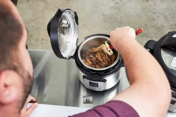 Pessoa cozinhando pratos na Panela de Pressão Multiuso Instant Pot Duo Mini 3-Quart, V5