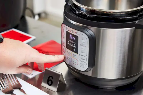 Pessoa pressionando Panela de Pressão Multiuso Instant Pot Duo Mini 3-Quart V5