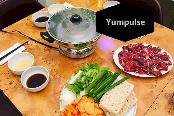 アロマ電気鍋は、食べ物や調理器具に囲まれたテーブルの上に置かれています。