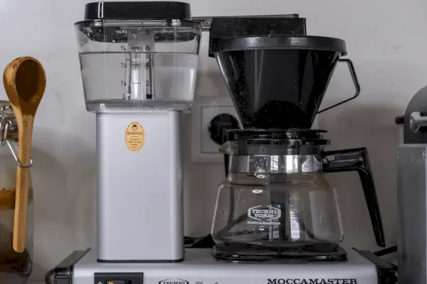 Uma mão segurando uma cafeteira suja