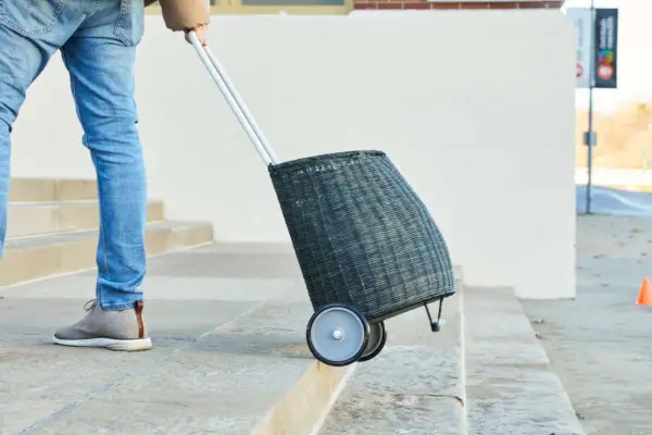 Olli Ella Wicker Luggy Basket을 외부 계단 위로 당기는 사람