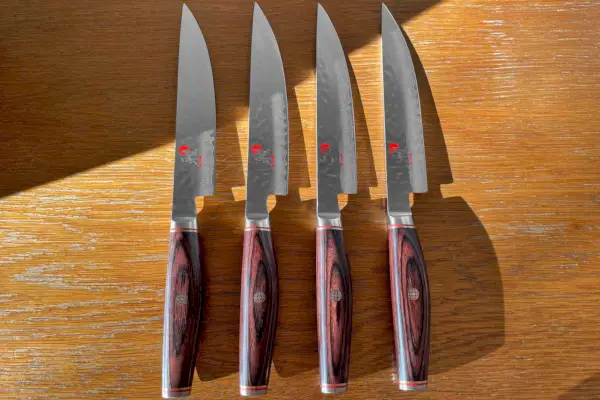 סט סכיני סטייק Miyabi Artisan 4 חלקים מוצג על שולחן עץ
