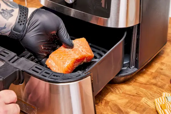 Personne préparant du poulet dans une friteuse à air Ninja de 4 litres