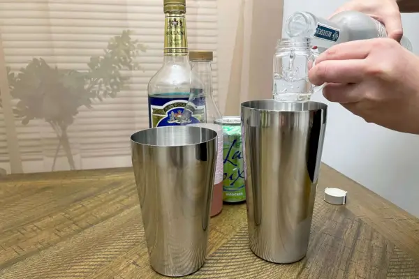 Person gießt Shots in den True Advance Edelstahl-Boston-Shaker