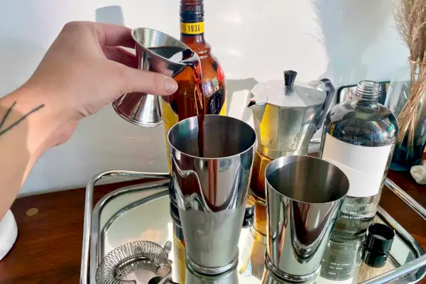 Person, die Shots in das Leopold Weighted Shaking Tin Set von Cocktail Kingdom einschenkt