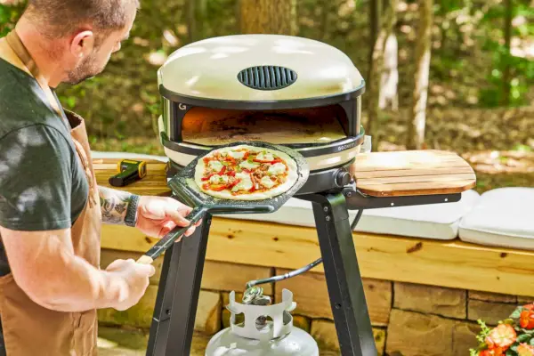 Osoba wprowadzająca surową pizzę do Gozney ARC