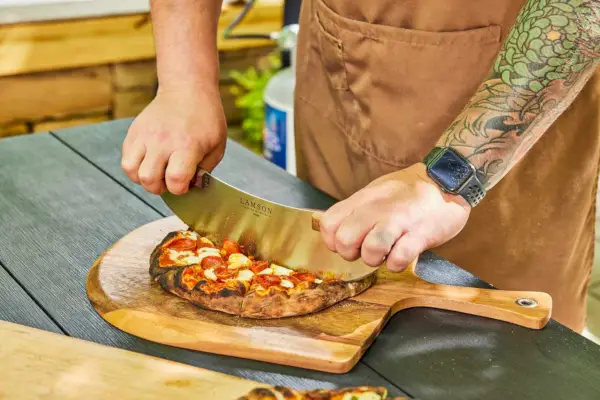 Osoba krojąca pizzę zrobioną w Gozney ARC