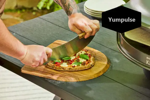Osoba krojąca ciasto do pizzy wykonane w piekarniku Everdure KILN S Series