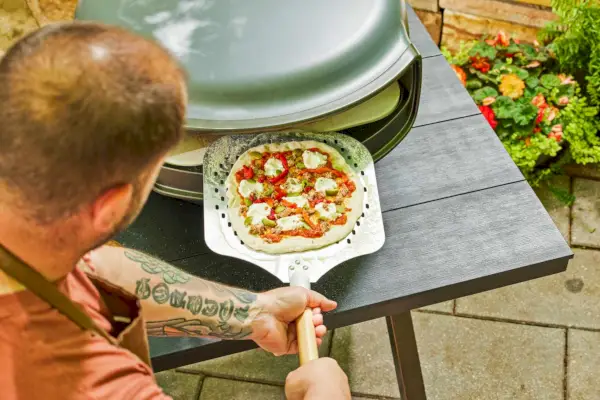 Osoba wkładająca surowe ciasto do piekarnika Everdure KILN S Series