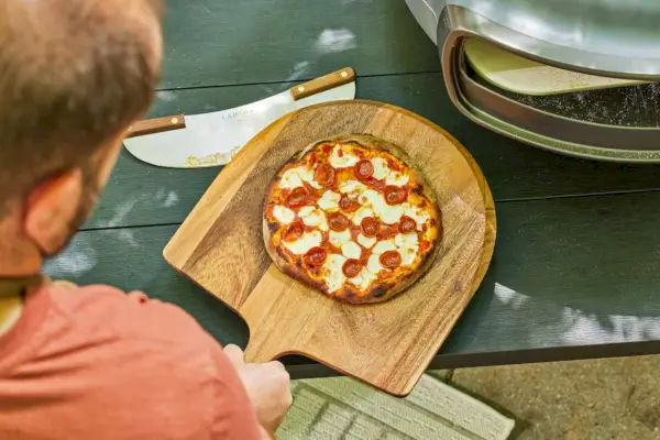 Osoba unosząca się nad pizzą zrobioną w piekarniku Everdure KILN S Series