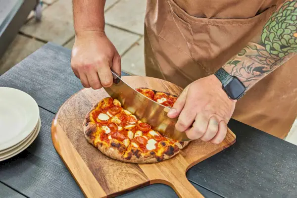 Osoba krojąca pizzę wykonaną w piecu do pizzy Alfa Forni Moderno 2