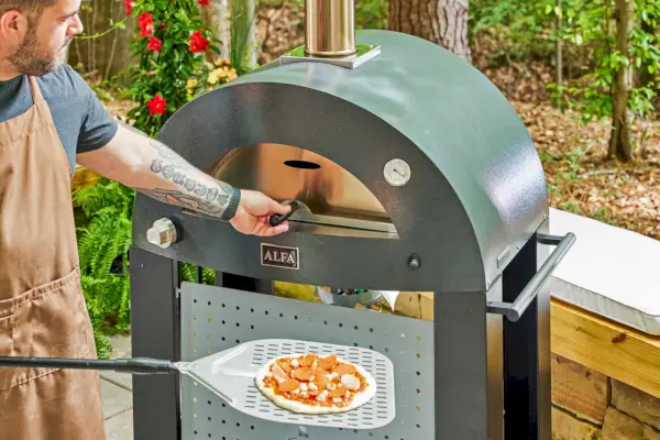 Osoba trzymająca ciasto podczas otwierania drzwi piekarnika do pizzy Alfa Forni Moderno 2