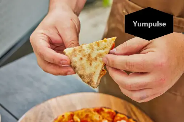 Dwie ręce trzymające kawałek pizzy przygotowanej w piecu do pizzy Alfa Forni Moderno 2