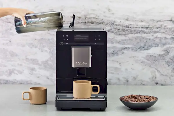 Gießen Sie von Hand Wasser in die automatische Kaffeemaschine und Espressomaschine Miele Silence