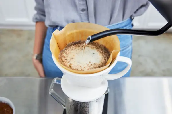 Pessoa despejando água na cafeteira e recipiente de porcelana Melitta Artisan