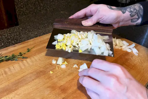 Une personne ramassant des légumes à l'aide du couteau d'établi de la King Arthur Baking Company