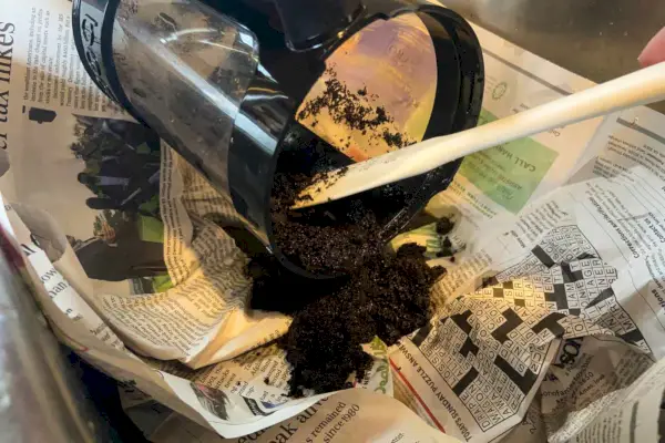 Uma pessoa despeja borra de café da cafeteira Bodum Bean Cold Brew no lixo