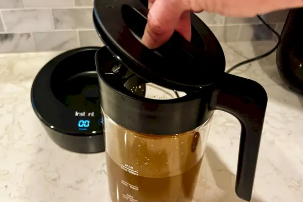 Uma pessoa remove a tampa da cafeteira elétrica fria instantânea