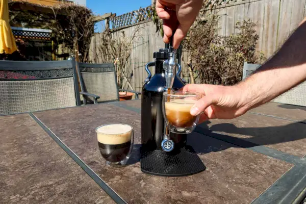 Uma pessoa serve café da cafeteira GrowlerWerks uKeg Nitro Cold Brew em um copo