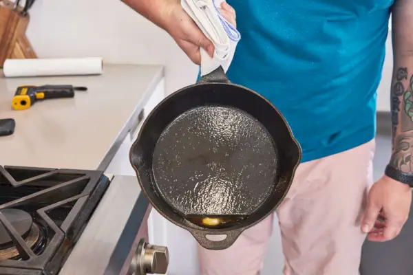 Person hält die Camp Chef 10 Seasoned Gusseisenpfanne mit Ölrückständen in der Hand