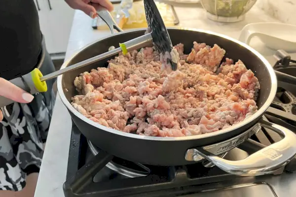Uma pessoa usa o espremedor de batatas dobrável Joseph Joseph para amassar uma refeição no fogão.