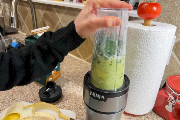 Osoba, ktorá mixuje zelené smoothie v kompaktnom osobnom mixéri Ninja BN301 Nutri-Blender Plus