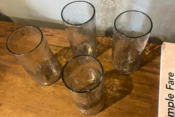 Il set di quattro bicchieri da bere artigianali Pottery Barn alti martellati su un tavolo di legno