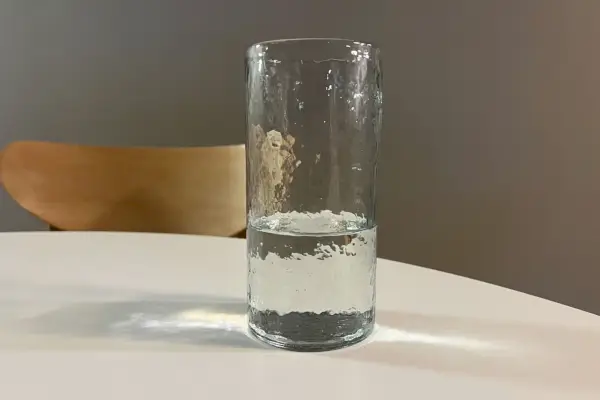 Un bicchiere d'acqua alto martellato artigianale in ceramica su un tavolo