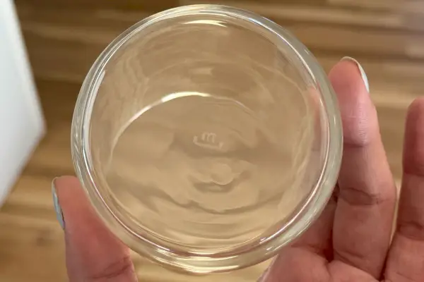 Una persona solleva la parte inferiore del bicchiere Made In Drinking Glass mostrando il logo del marchio