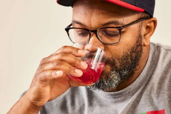 Una persona sorseggia un liquido rosso da un set di tumbler in vetro Bormioli Rocco Bodega Mini da 7,5 once