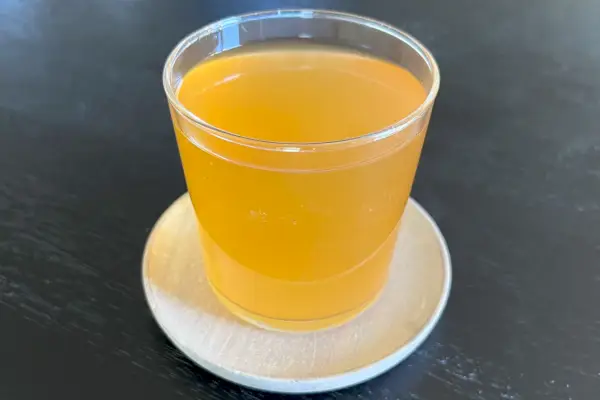 Bicchiere in vetro della collezione Bormioli Rocco Bodega riempito con liquido arancione sopra un sottobicchiere