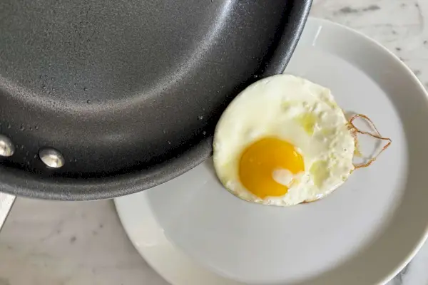 Ein in der Tramontina 10-Zoll Professional Aluminium Antihaft-Restaurant-Bratpfanne gekochtes Ei wird auf einen Teller gelegt