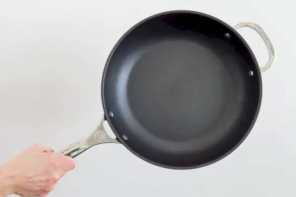 Eine Person hält die Le Creuset Toughened Nonstick PRO Frittierpfanne hoch