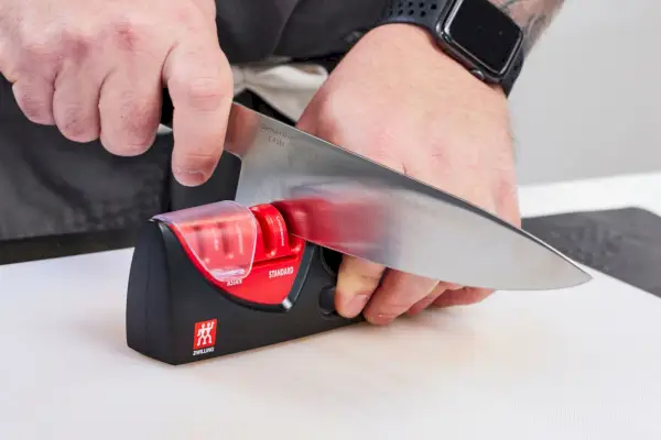 אדם משחיז סכין באמצעות ה-ZWILLING J.A. מחדד סכינים 4 שלבים של Henckels