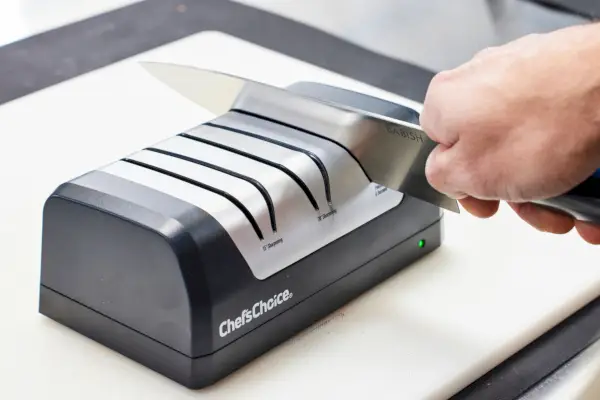 אדם משחיז סכין במחדד החשמלי של ChefâChoice DCB1520 AngleSelect הנטען